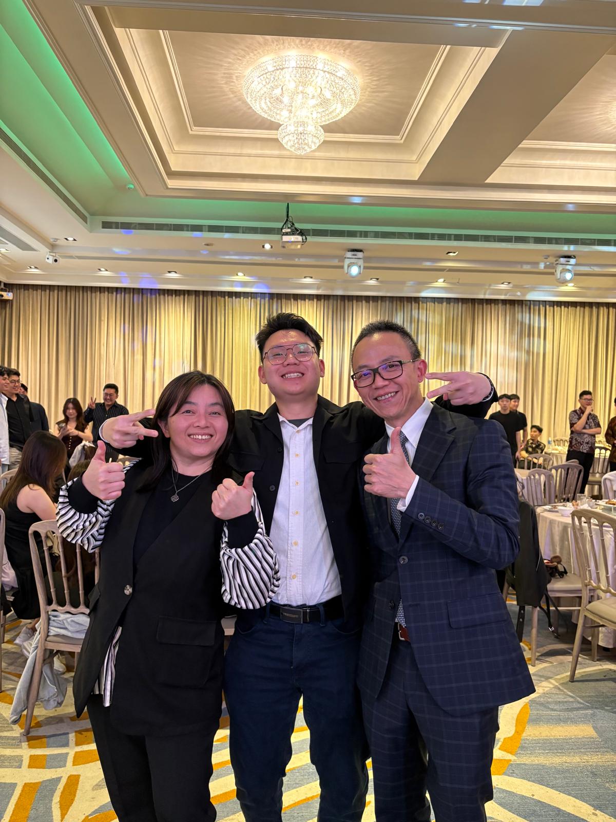 Jonathan smiling with Bai Laoshi and a companion at an event